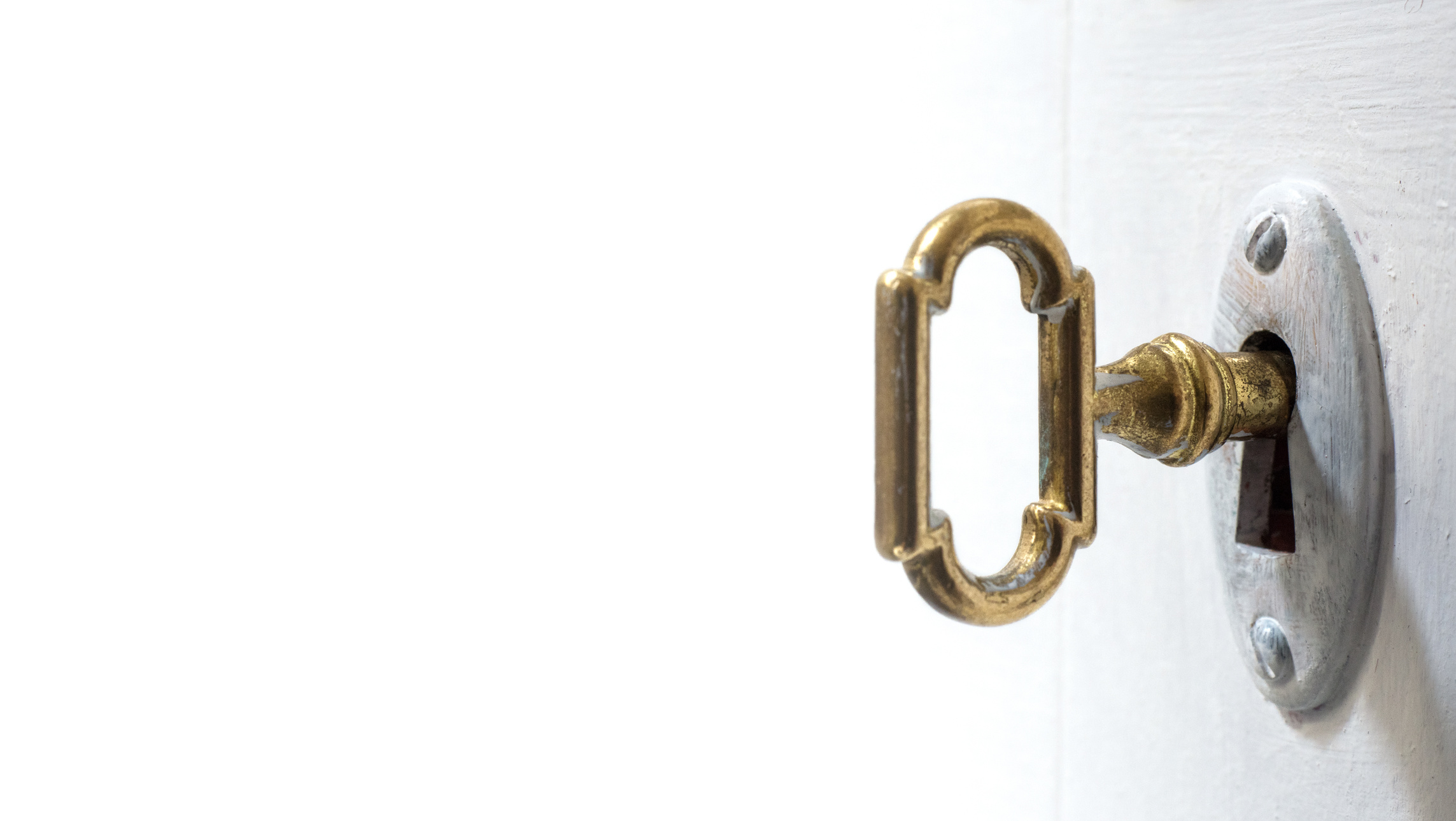 Old key in keyhole, macro shot, white background.